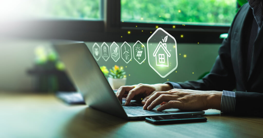 Person sitzt am Notebook: In der Luft holografische Symbolbilder Haus und Energie